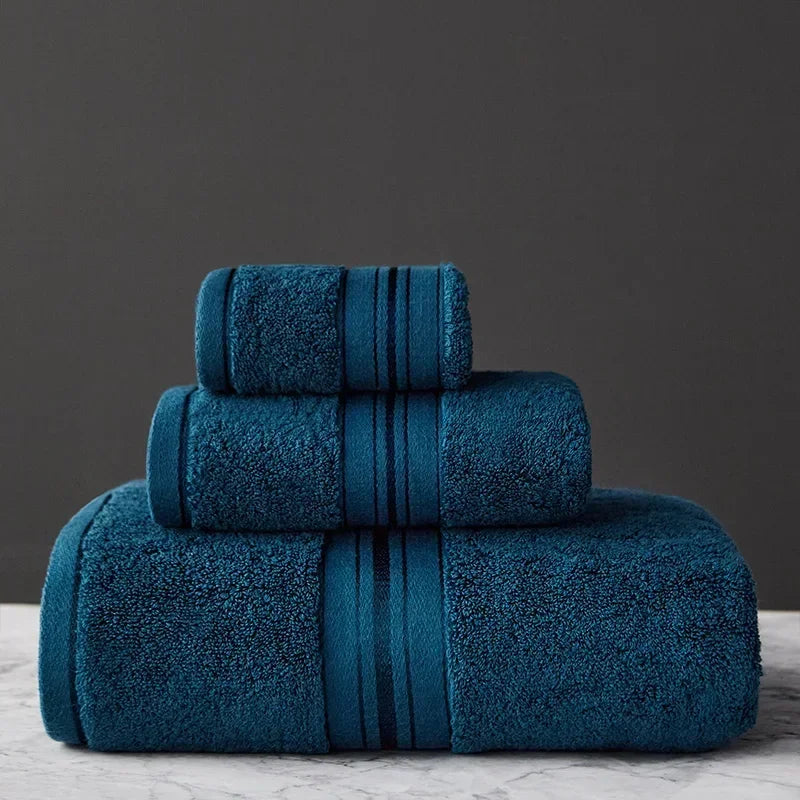 Set of three blue towels stacked on a gray surface with a dark gray background