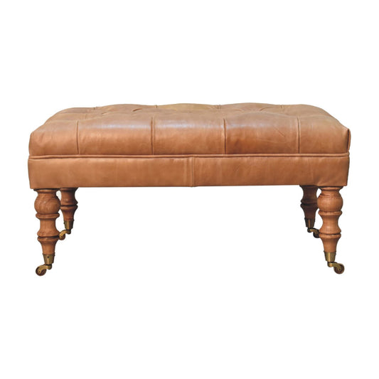 Tan buffalo leather ottoman with solid mango wood base, deep-buttoned top, and light walnut hand-turned feet.