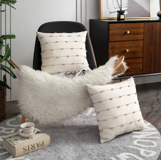 Decorative pillows on a chair with a wooden cabinet and plant in the background