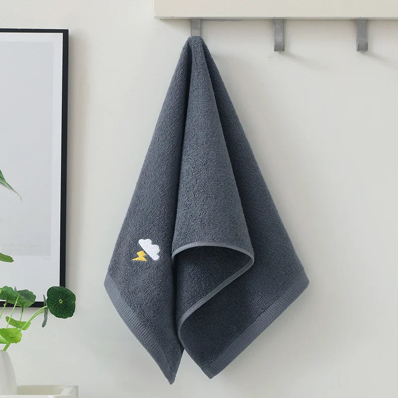 Gray towel with cloud design hanging on a hook against a white wall.