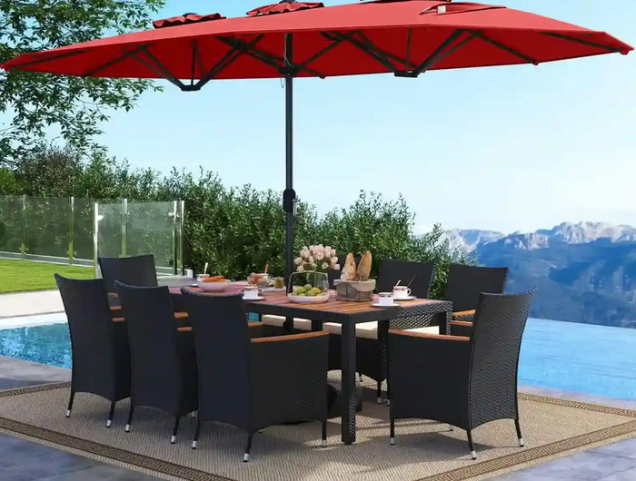 Outdoor dining setup with a large red umbrella, table, and chairs by a pool with mountains in the background.