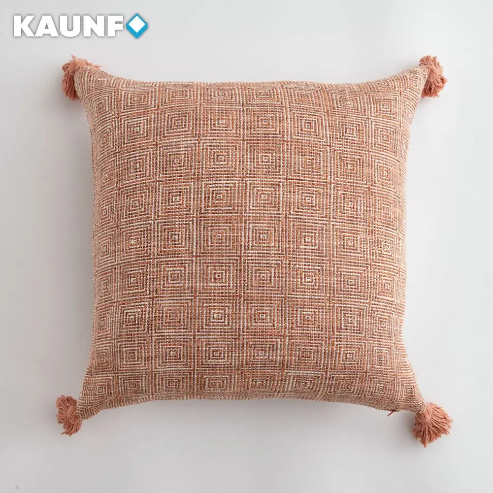 Decorative pillow with geometric pattern and tassels on a light background, branded 'KAUNF'.