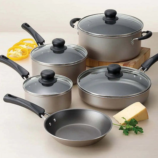 Set of stainless steel cookware with black handles on a light background