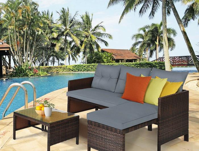 Outdoor patio furniture set with colorful cushions by a poolside with palm trees in the background.