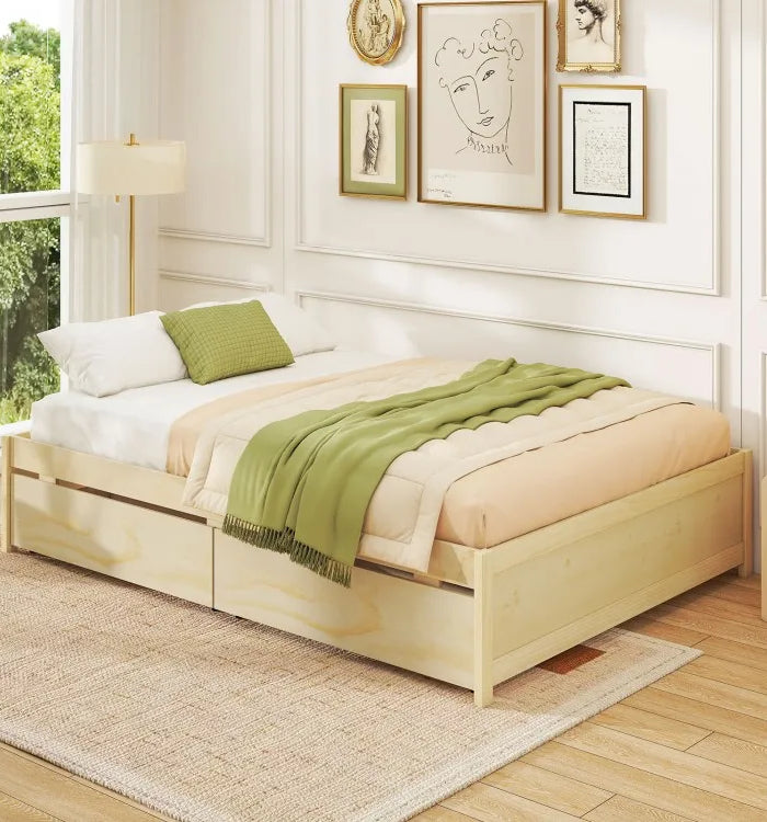 Wooden bed with white bedding and green blanket in a bright room with framed art on the wall.