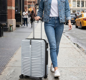 Person walking with a silver suitcase on a city street