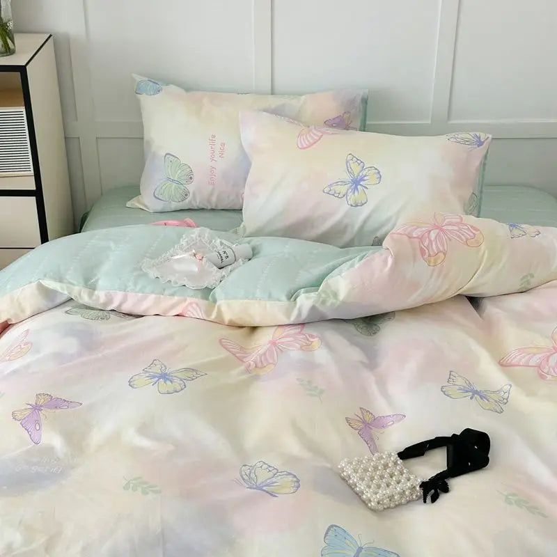 Pastel-colored bedding set with butterfly patterns on a bed.