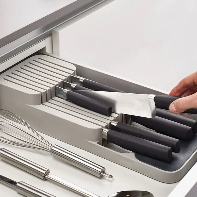 Knife set with black handles in a kitchen drawer organizer.