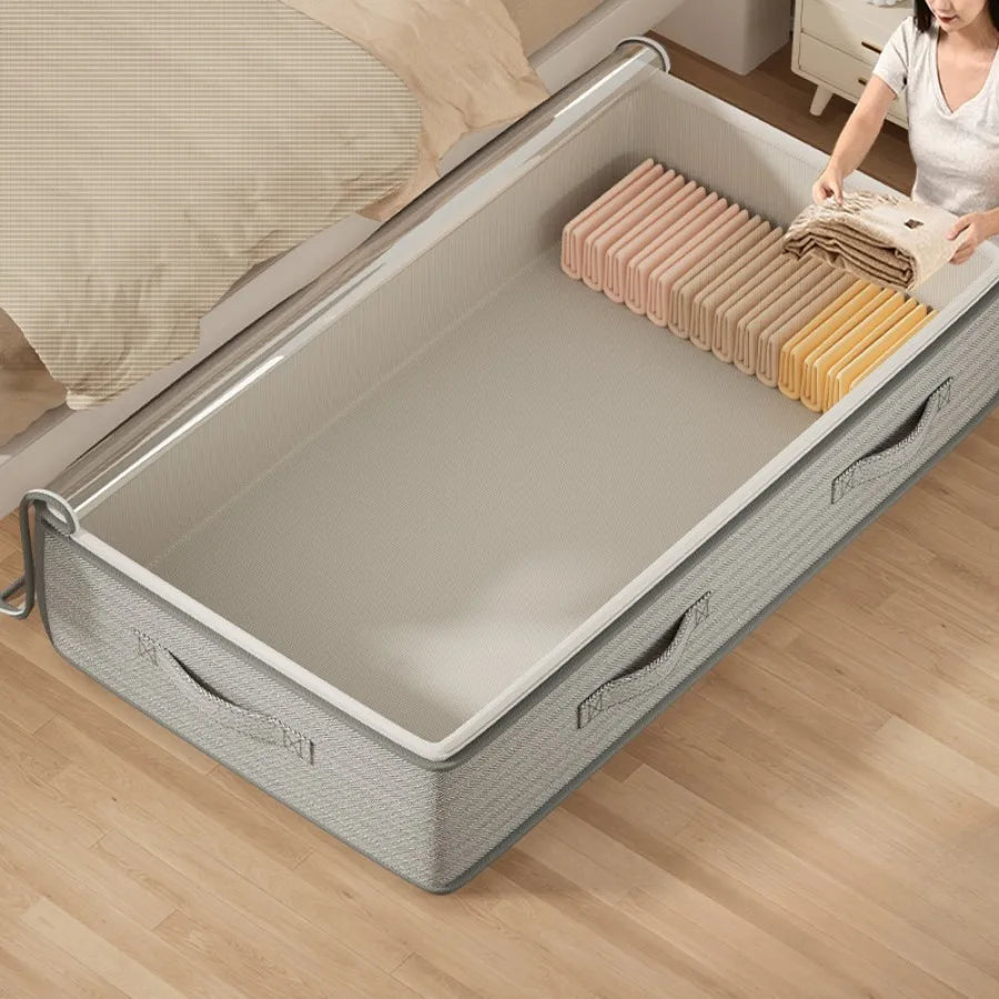 Gray storage box with clothes on a wooden floor next to a bed.