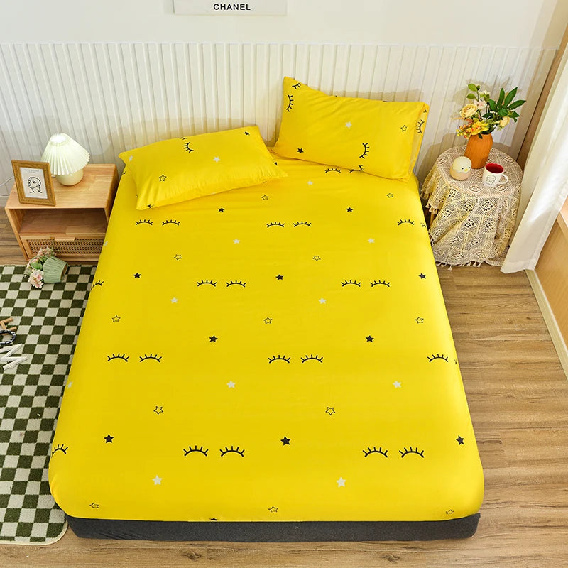 Yellow bedspread with black patterns on a bed in a room with a desk and lamp.
