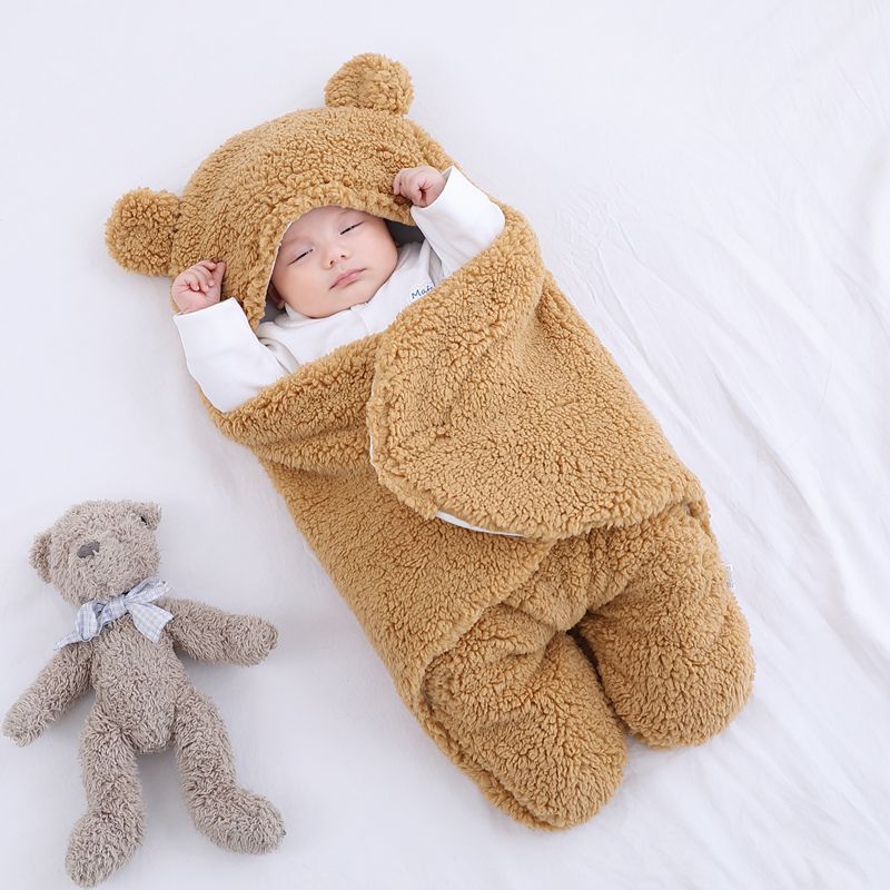Baby sleeping in a brown teddy bear outfit with a matching teddy bear on a white background