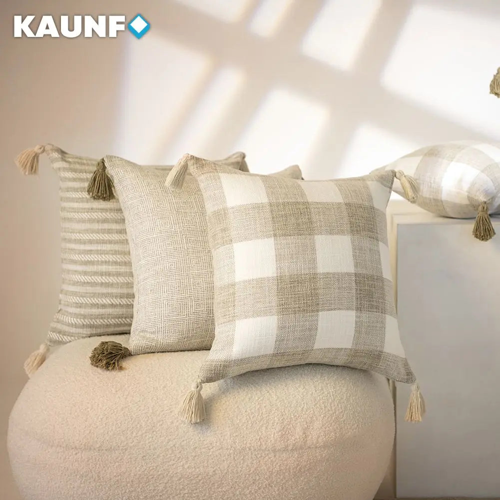 Decorative pillows with tassels on a neutral background, featuring the KAUNF brand.