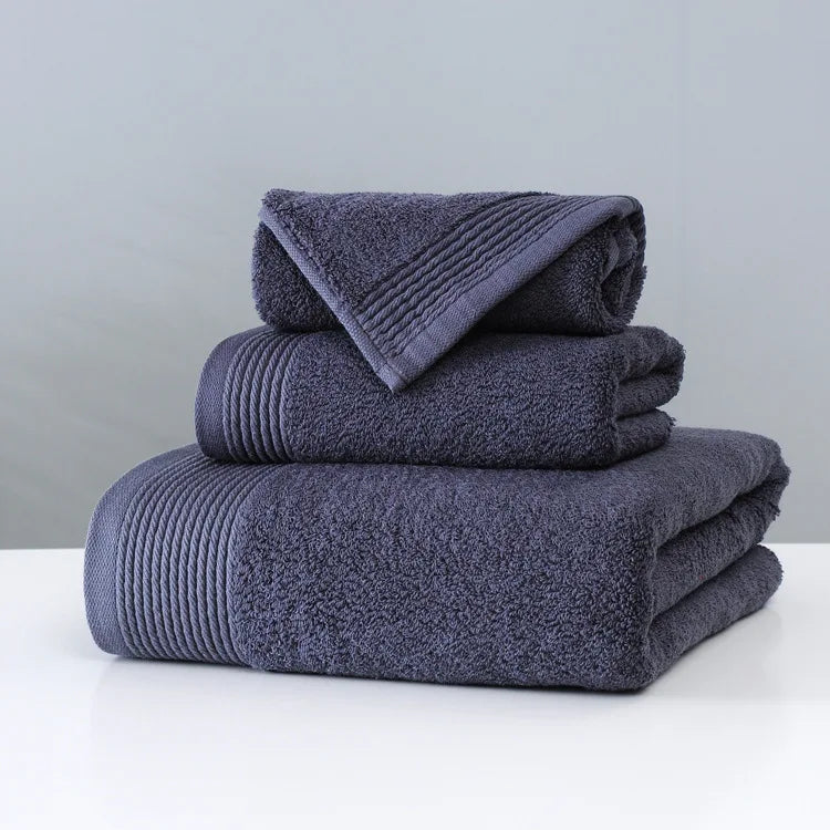 Stack of folded navy blue towels on a white surface with a gray background