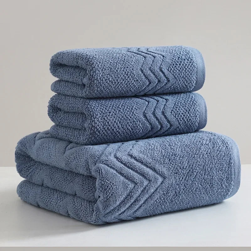 Set of three blue towels with textured pattern on a light gray background