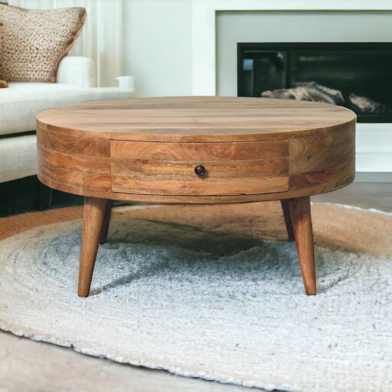 Odyssey Oak-ish Coffee Table made from solid mango wood with circular design and drawer with brass knob. View of table in a living room