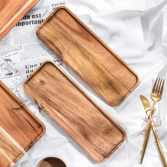 Two wooden trays on a white surface with gold cutlery.