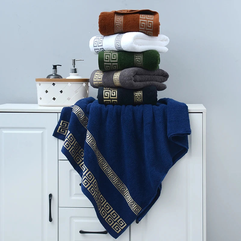 Stack of towels with decorative patterns on a white cabinet against a gray wall.
