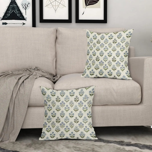 Decorative pillows with floral patterns on a beige sofa against a gray wall with framed artwork.