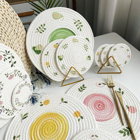 Set of round woven placemats with floral and geometric designs on a table.