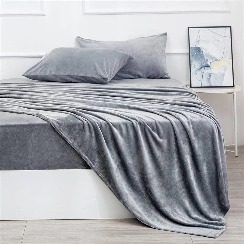 Gray bedding set on a bed in a bedroom with a framed picture on the wall.