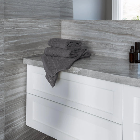 Gray towels on a bathroom counter with a tiled wall background