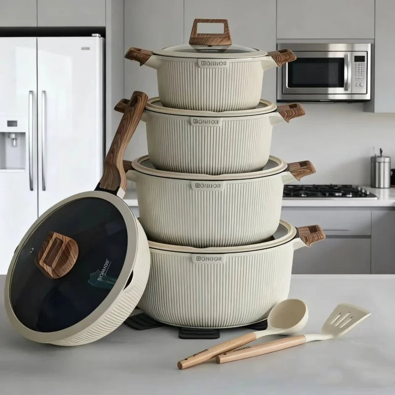 Set of stacked ceramic cookware with wooden handles on a kitchen counter.