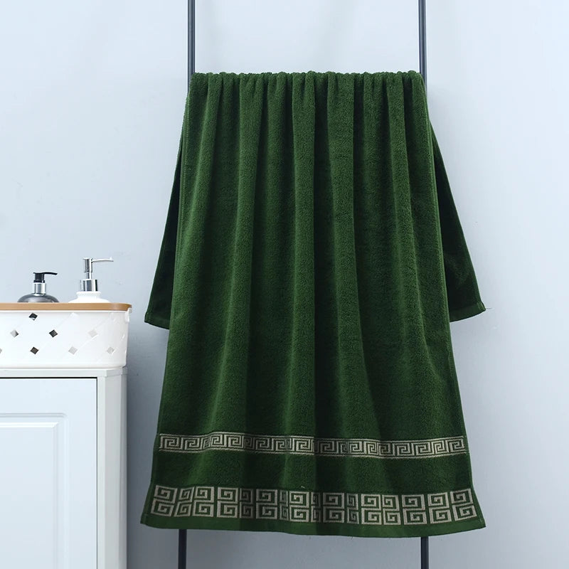 Green towel with a pattern hanging on a rack against a white wall.