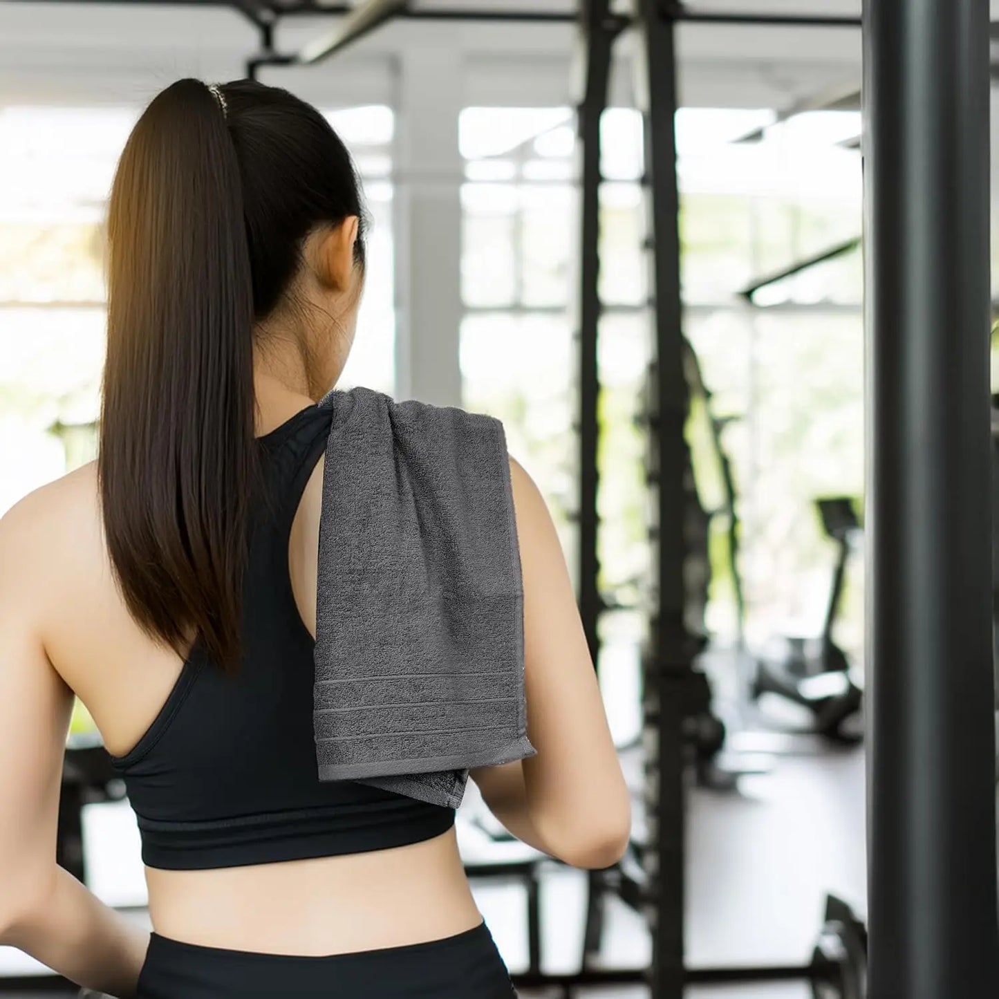 Woman in a gym holding a gray towel over her shoulder