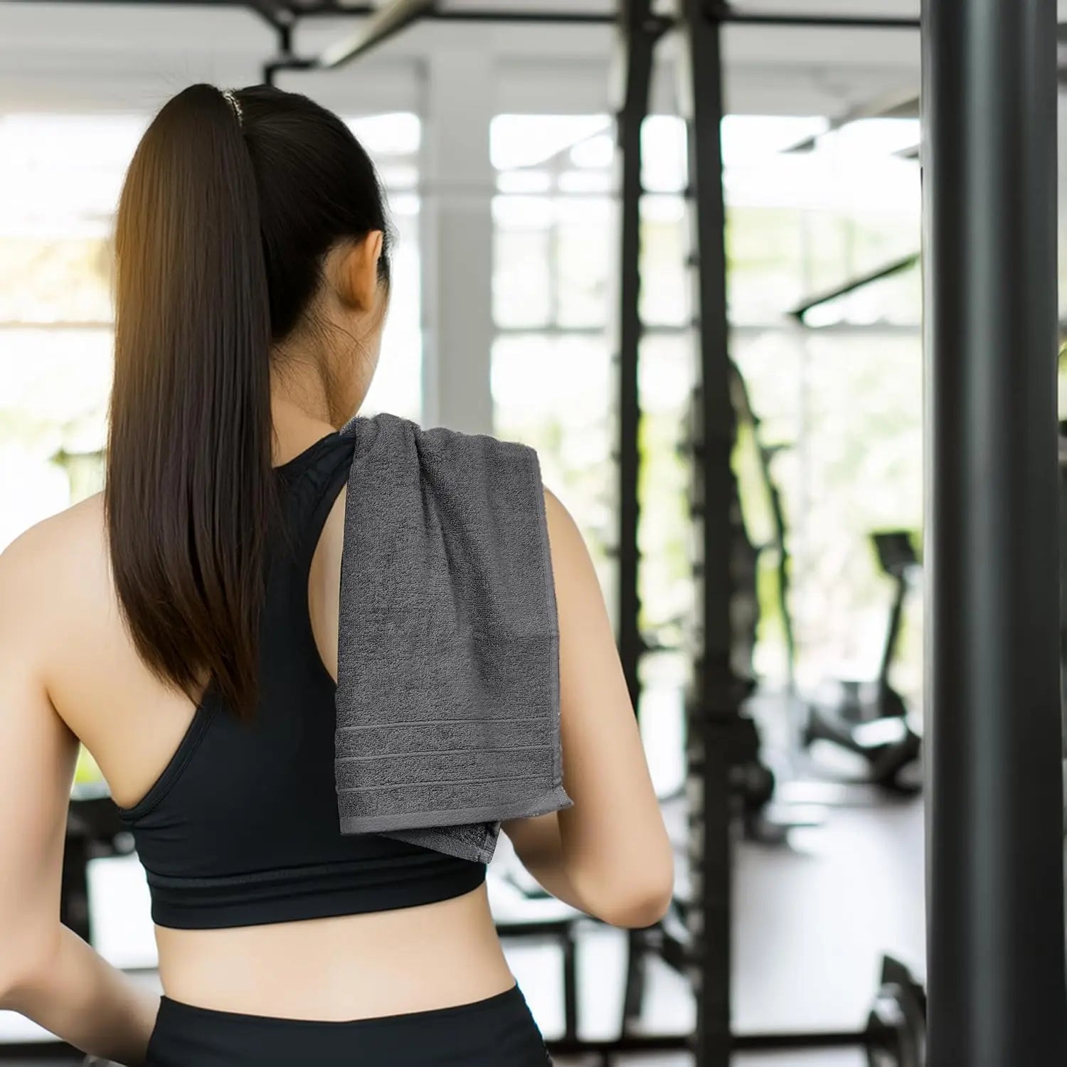 Woman in a gym holding a gray towel over her shoulder