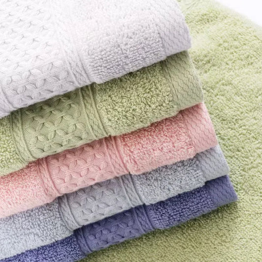 Stack of folded towels in various colors on a green surface