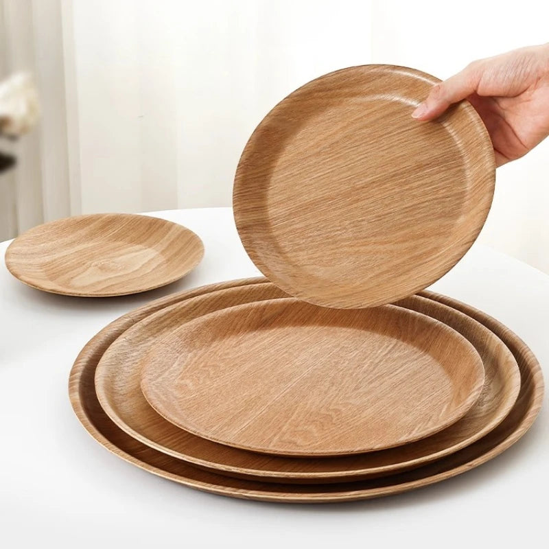 Set of wooden plates on a white surface with a hand lifting one plate.