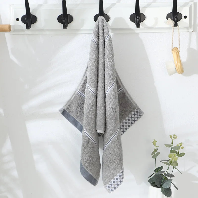Gray hand towel hanging on a rack with a plant in the corner