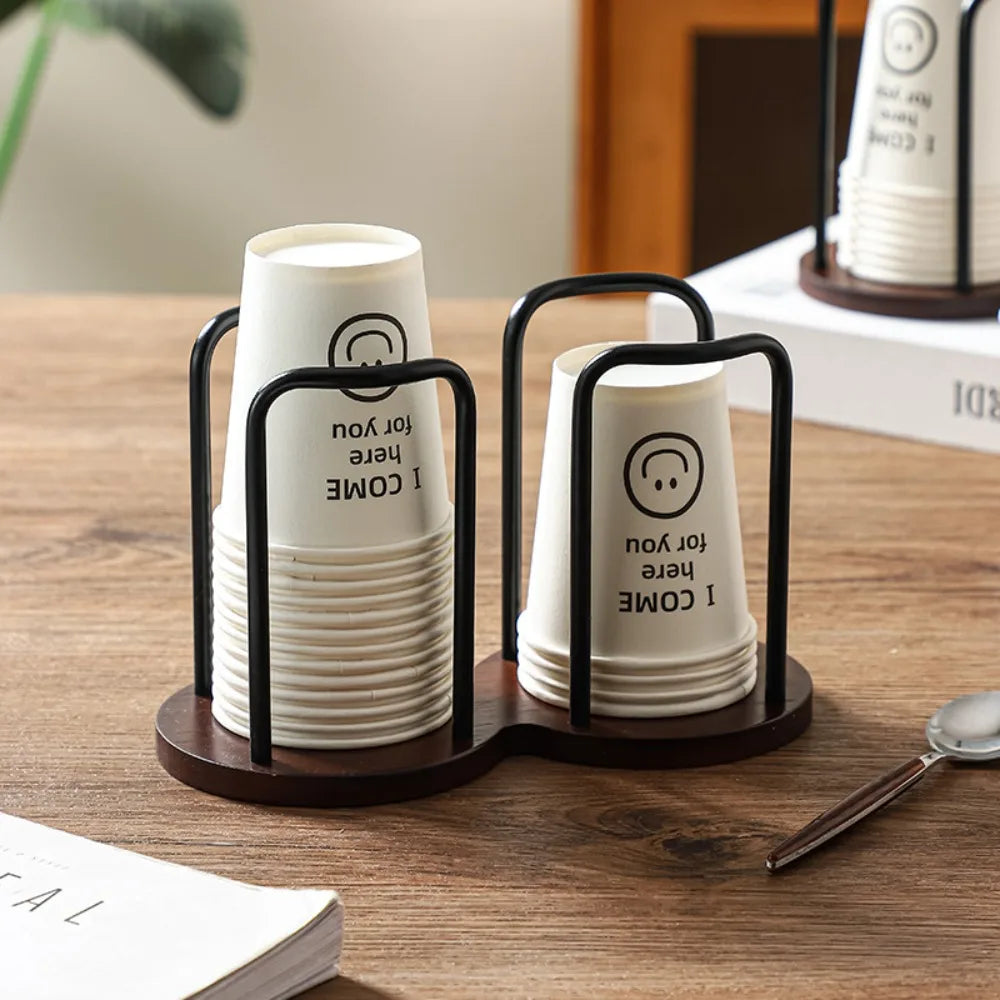 Stack of white cups with text in a black holder on a wooden surface.