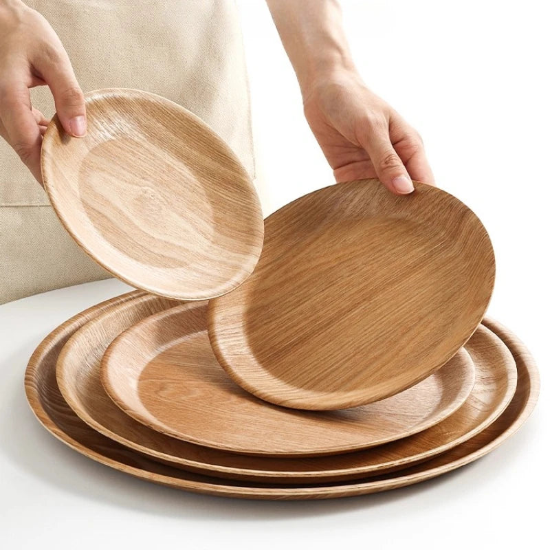 Wooden plates being held above a stack of wooden plates on a white surface.