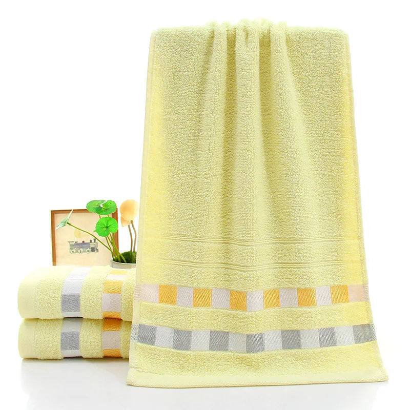 Yellow bath towel with striped border on a white background