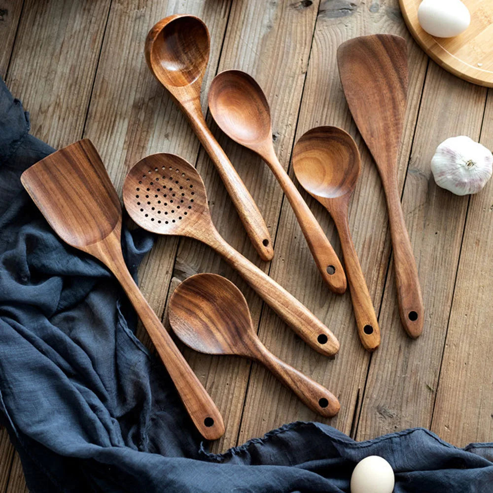 Set of wooden cooking utensils on a wooden surface with a blue cloth underneath.