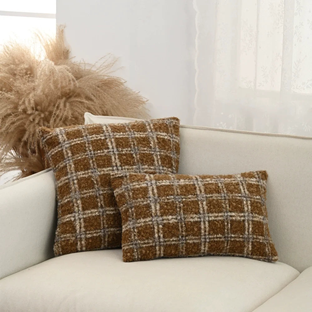 Plaid throw pillows on a white sofa with decorative pampas grass.