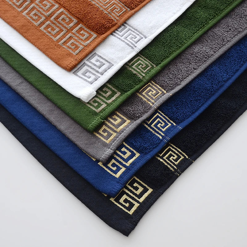 Set of folded towels in various colors with a geometric pattern on a light gray background