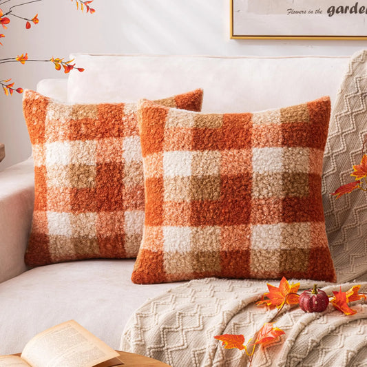 Two plaid patterned pillows on a sofa with decorative elements.
