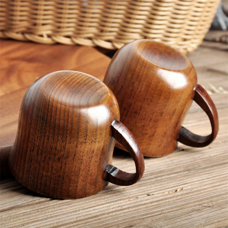Two wooden mugs on a wooden surface with a woven basket in the background.