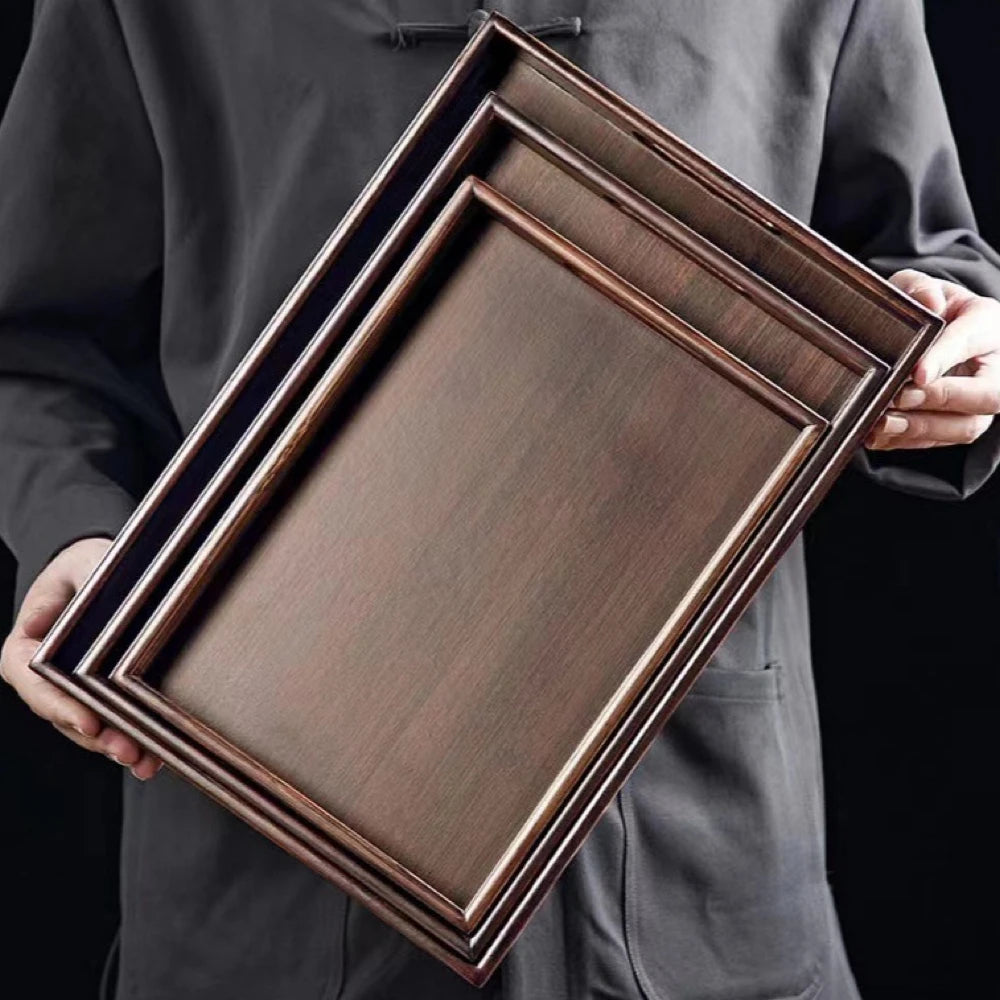Person holding three wooden trays with a dark finish