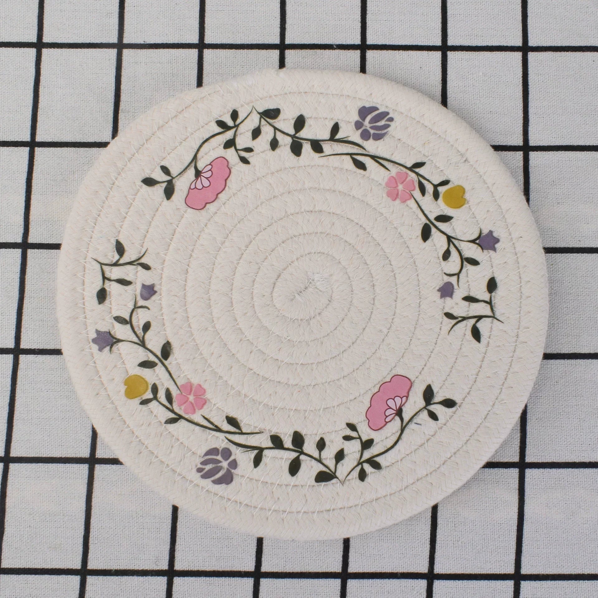 Round woven coaster with floral design on a grid background
