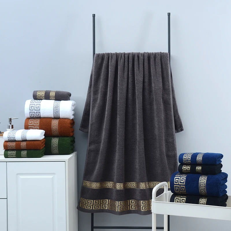 Stack of folded towels including a dark gray one with a pattern, on a white cabinet against a light blue wall.