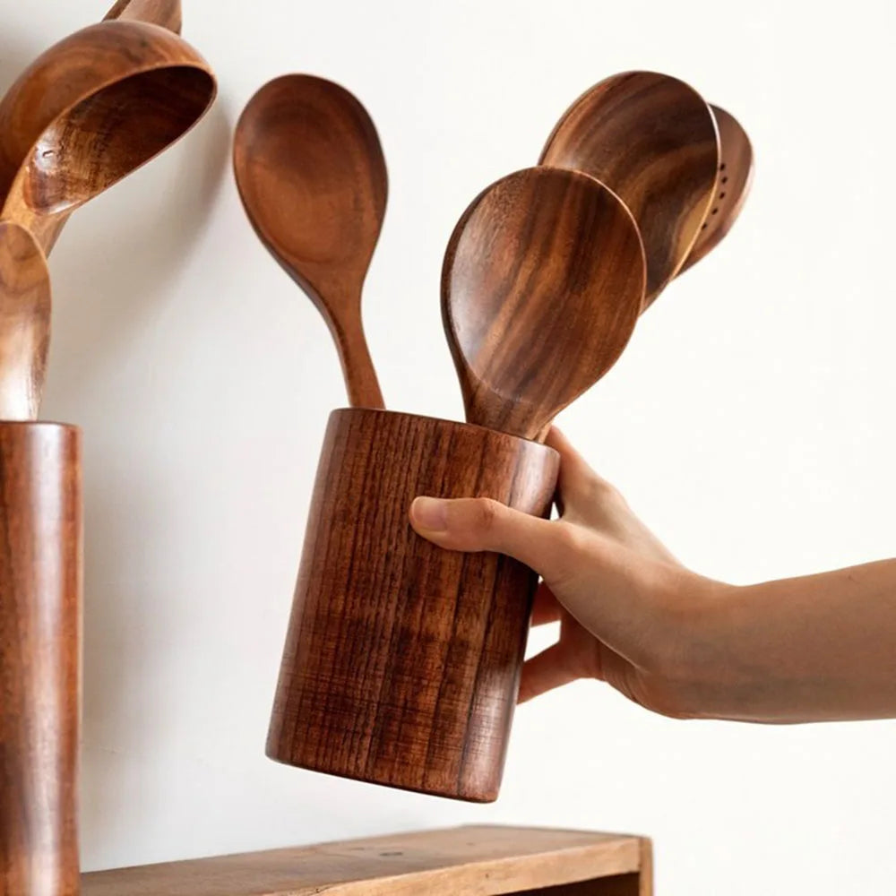 Wooden utensils in a holder held by a hand against a white background