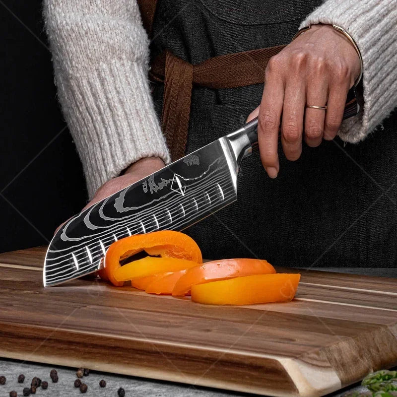 Person using a chef's knife to slice orange bell peppers on a wooden cutting board.
