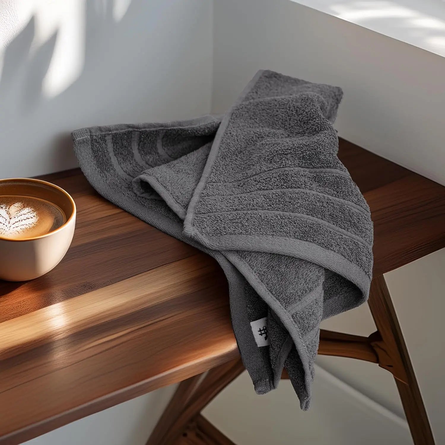 Gray towel draped over a wooden surface with a blurred coffee cup in the background