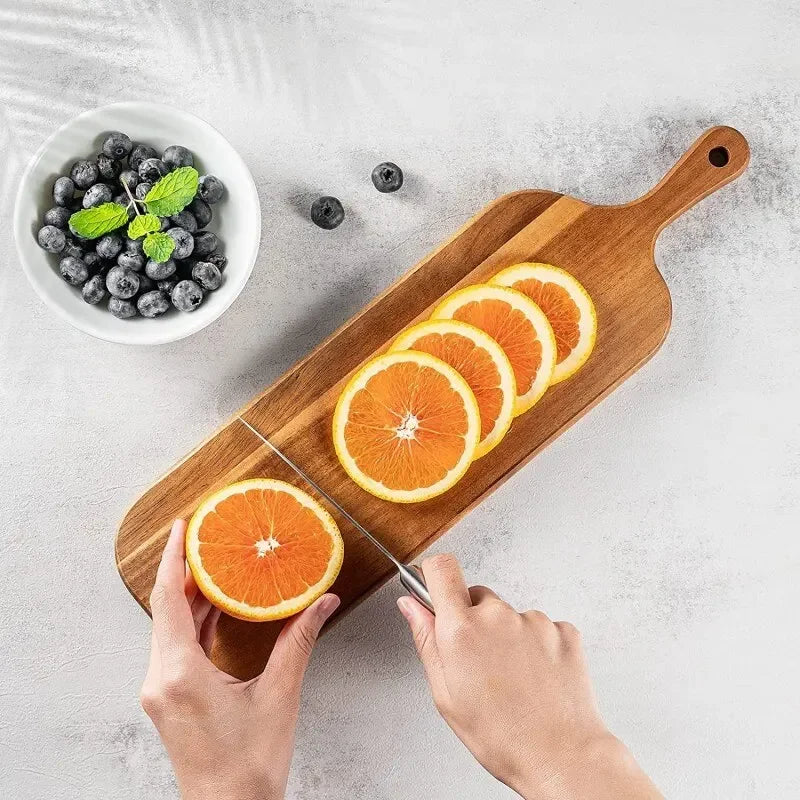 Sliced oranges on a wooden cutting board with a bowl of blueberries and mint leaves.