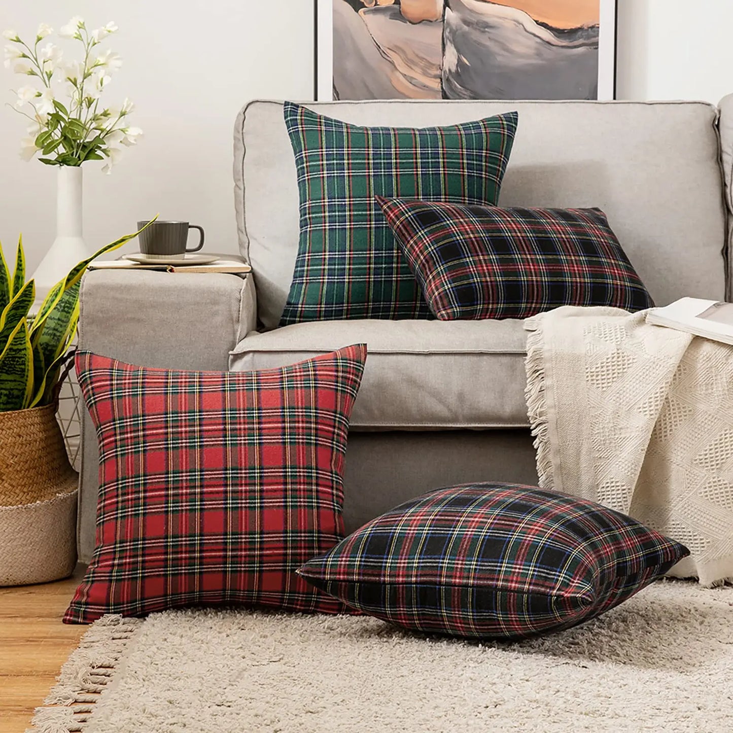 Plaid pillows on a gray sofa with a decorative plant and framed art in the background.