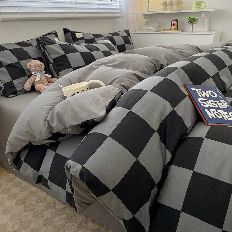 Checkered bedspread on a bed with pillows and a teddy bear in a bedroom setting.