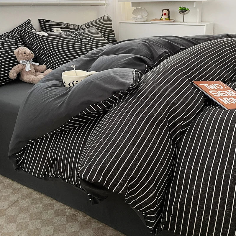 Black and white striped bedding set on a bed with a teddy bear and bowl.